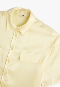 Korte mouwen, lichtgele knoopschalige shirt in een geribbelde textuur, met een klassieke kraag en een borstzak. Gemaakt van een gladde stof.