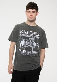 Gray graphic t-shirt featuring the "Ramones" logo and performance studio details in white, with a relaxed fit and short sleeves.