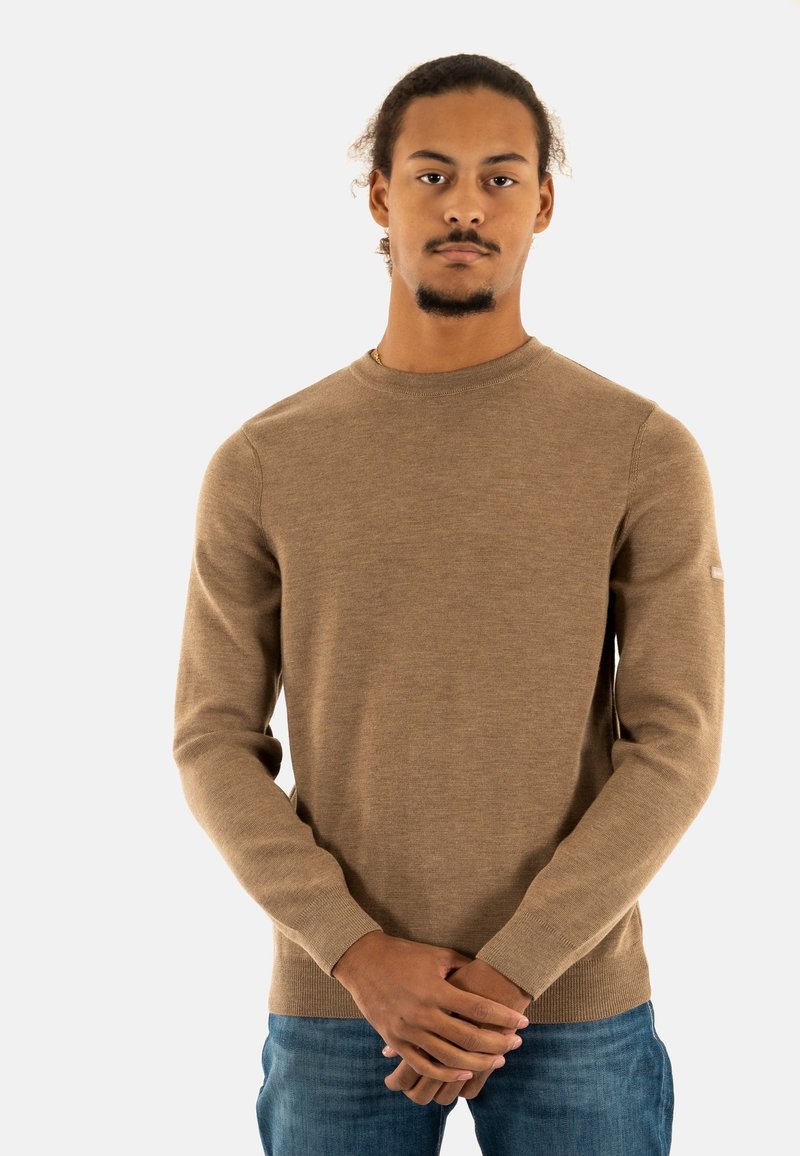 Maglione marrone a maniche lunghe con colletto rotondo, polsini a coste e lavorazione a maglia testurizzata. Abbinato a jeans in denim blu.