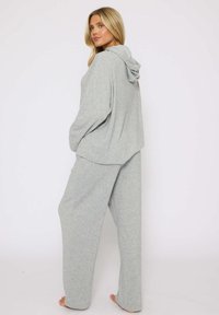 Conjunto de ropa de lounge texturizado en gris claro, que incluye una sudadera con capucha y pantalones holgados, ambos con una silueta relajada y sin patrones visibles.