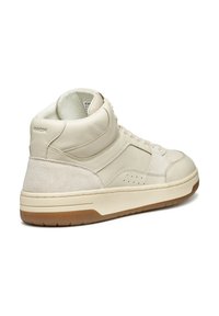 Zapatilla alta de cuero crema con acentos de serraje, detalles perforados y suela de goma texturizada. Punta redondeada y cuello acolchado.