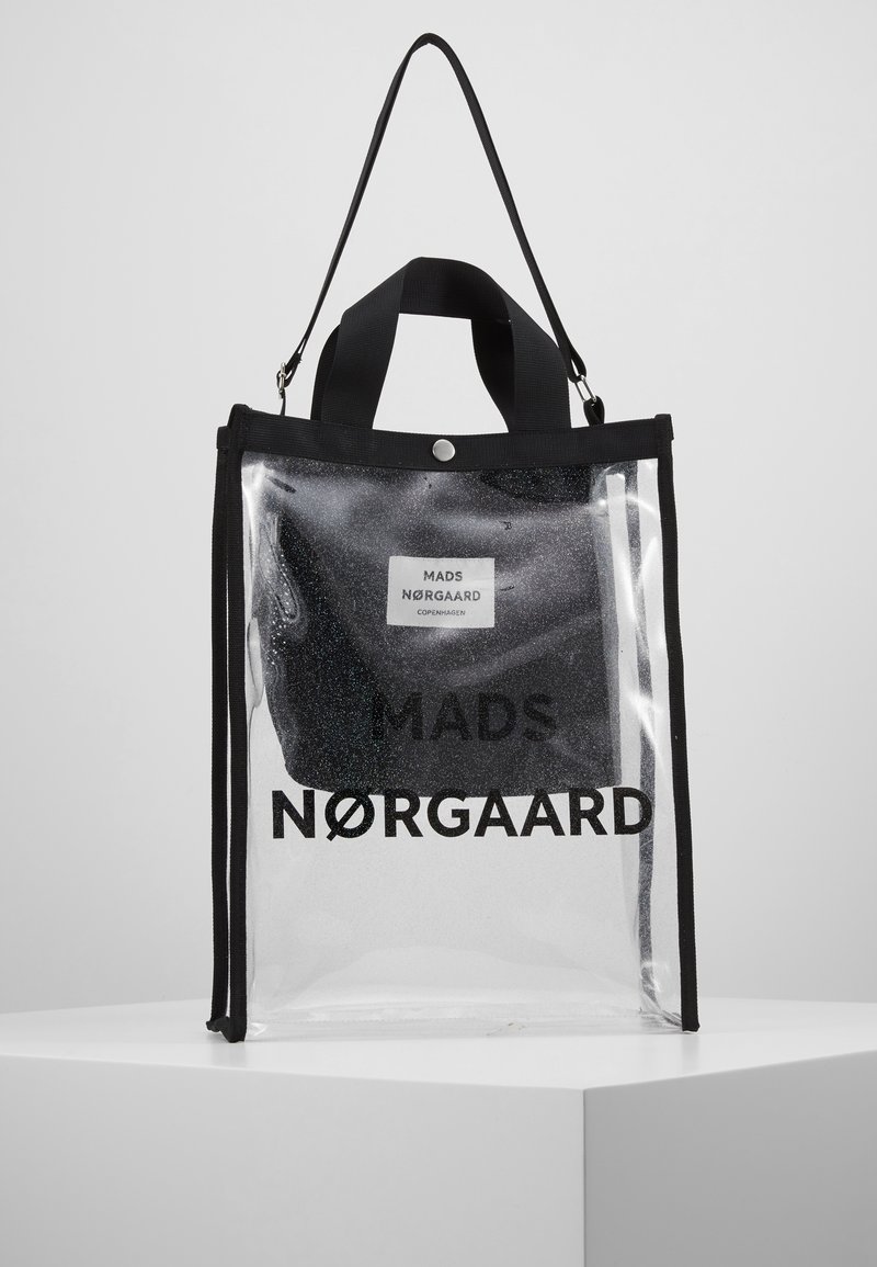 Sac fourre-tout transparent avec bordure et poignées noires, contenant une pochette noire plus petite étiquetée MADS NØRGAARD COPENHAGEN.