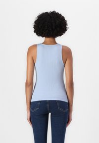 Hellesblaues, geripptes Tanktop mit rundem Ausschnitt und schmalen Trägern, kombiniert mit dunkelblauen, figurbetonten Jeans.