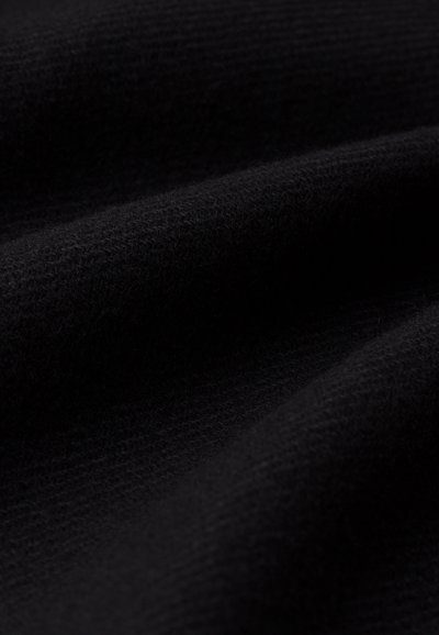 Material textil de culoare neagră cu un finisaj moale și texturat, care pune în evidență pliuri și reflecții ale luminii variate, demonstrând profunzime și calitate a materialului.