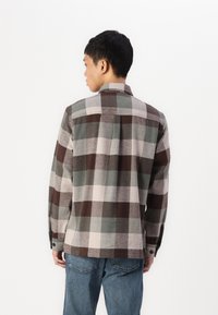 Button-up rutete skjorte i grå, brun og krem. Laget av myk stoff med krage, lange ermer og rett hem. To-knapps mansjetter.