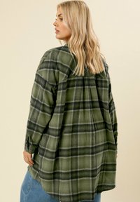Camicia a maniche lunghe a quadri verde con una vestibilità rilassata, dotata di piega posteriore e polsini abbottonati. Tessuto morbido con una finitura strutturata.