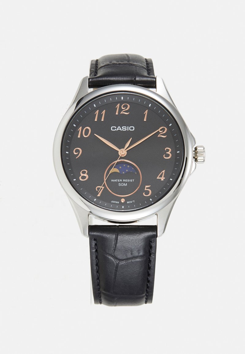 Kerek analóg óra fekete számlappal, rózsaarany számokkal és krokodilmintás fekete bőr szíjjal. 50 méterig vízálló.