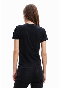 Černé tričko s krátkým rukávem, vyrobené z bavlny, má kulatý výstřih, přiléhavý střih a hladkou texturu. Pohled zezadu ukazuje jednoduchý design bez ozdob.