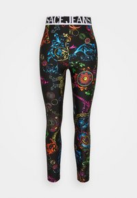Černé legíny s barevnými barokními a řetězovými vzory, s bílým elastickým pasem, na kterém je tučně napsáno "VERSACE JEANS".