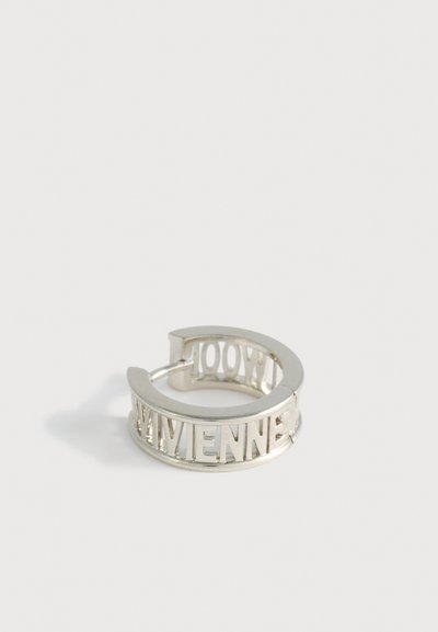 Anillo de plata con letras recortadas que deletrean "VIVIENNE," con un acabado liso y pulido y una forma circular.
