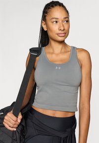 Γκρι αθλητικό crop top με άνετη σχεδίαση χωρίς ένωση, ριμπ υφή και μικρό λογότυπο στο στήθος, συνδυασμένο με μαύρο κολάν και σακ βουαγιάζ.