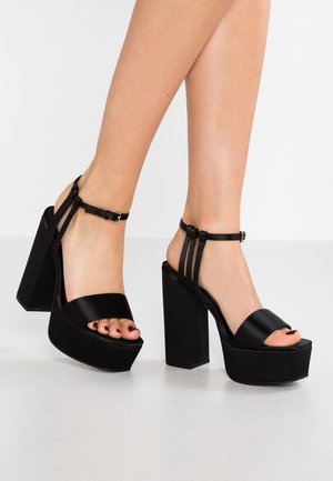 Schwarze Absatzsandalen mit einem eleganten Satinfinish, einem breiten Vorderband und mehreren Knöchelriemen, mit einer klobigen Plattform und Blockabsatz.