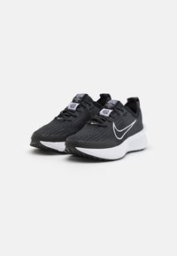 Sorte atletikskoler med et tekstureret mesh-overmateriale, hvide accenter og en polstret sål. Har et sort snøresystem og en trække-øjeblik.