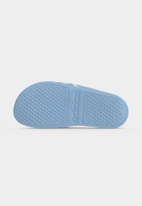 Semelle de sandale Adidas slide bleu clair avec motif antidérapant texturé et logo Adidas embossé sur fond blanc.