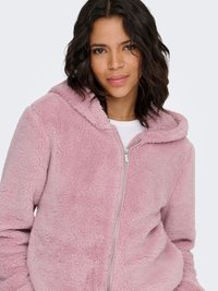 Sweat à capuche zippé en polaire rose avec une finition texturée et une capuche. Il est équipé d'une fermeture éclair argentée et de poches latérales, offrant une coupe décontractée.