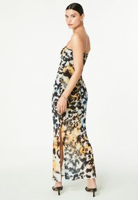 Trägerloses Maxikleid mit einem mehrfarbigen Leopardenmuster in Schwarz, Orange und Blau, seitlichem Schlitz und figurbetonender Silhouette.
