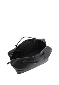Sac de voyage en cuir noir avec une grande fermeture éclair, des poignées robustes et une surface texturée. L'intérieur est spacieux avec un revêtement sombre.