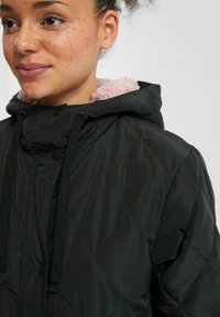 Zwarte gewatteerde jas met een roze fleece-voering in de capuchon, met trekkoorden en knoopsluitingen, een gladde buitenkant en een omlijnd stikselpatroon.