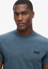 T-shirt blu con maniche corte realizzato in tessuto texturizzato, caratterizzato da un collo rotondo e un piccolo logo nero sul petto sinistro.