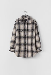 Kostkovaná flanelová košile v černé a béžové barvě s předním zapínáním na knoflíky, límečkem a dvěma náprsními kapsami. Měkká textura, dlouhé rukávy a volný střih.