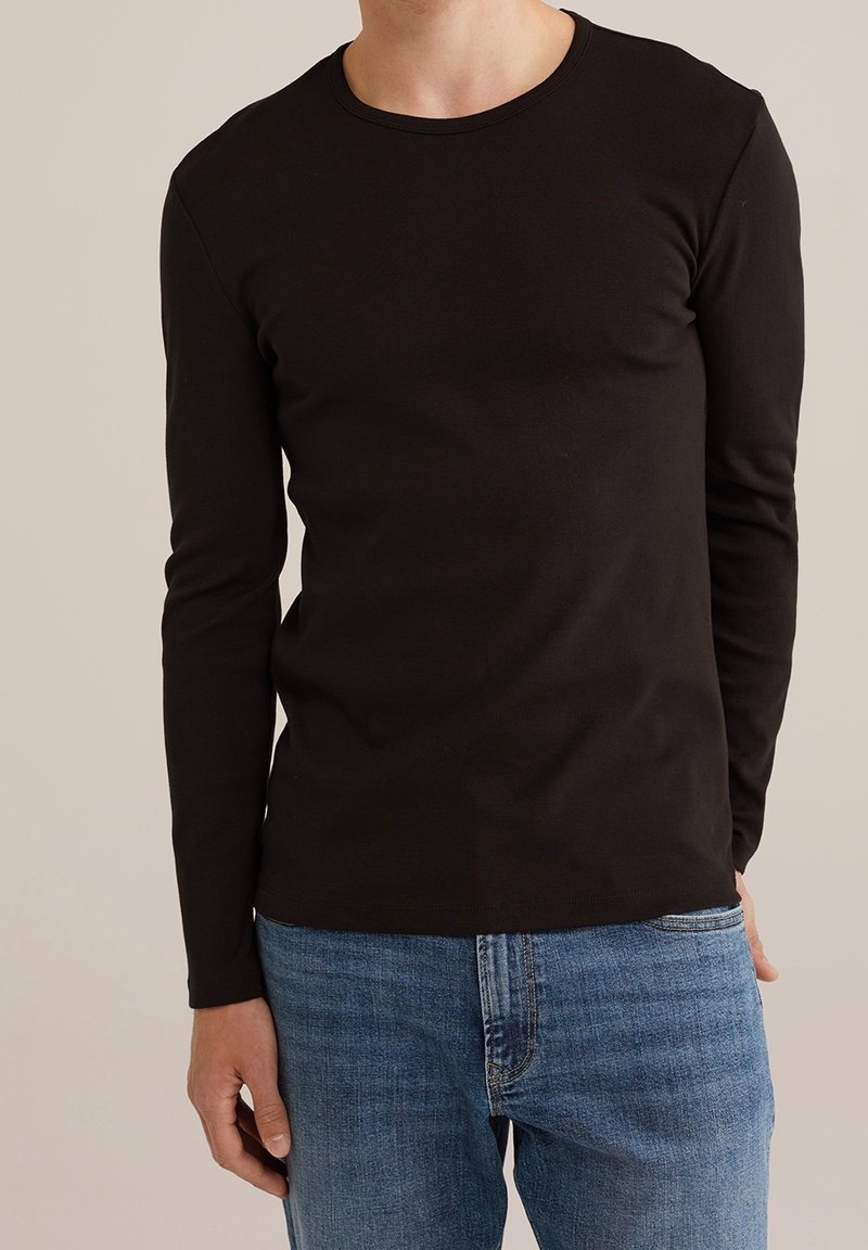 Svart långärmad T-shirt i mjukt bomullsmaterial, med rundad hals och smal passform. Matchas med blå denimjeans.