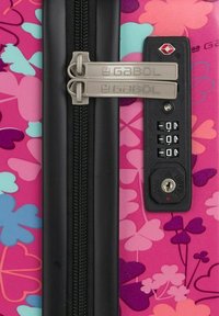 Valigia rigida di colore rosa con motivi floreali in blu, viola e bianco. Presenta doppie cerniere, una serratura a combinazione e dettagli in plastica.