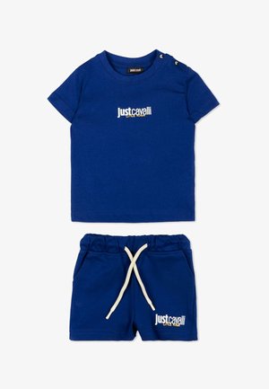 Niebieski zestaw dziecięcy z krótkim rękawem i szortami ozdobiony białymi napisami „Just Cavalli Little Rogue” oraz białym sznurkiem w szortach.