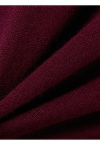 Bordeaux gebreid stof met een zachte textuur, gekenmerkt door fijne ribbels en een lichte glans, gevouwen om diepte en gelaagdheid te tonen.