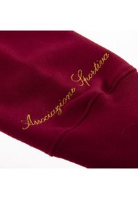 Bordeauxkleurige stof met een gladde textuur; bevat gouden geborduurde tekst "Associazione Sportiva" langs de zijkant.