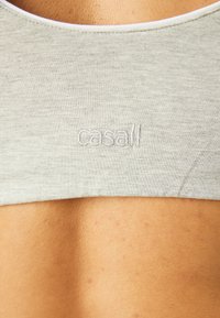 Gray sports bra with a seamless design, soft texture, and an embroidered "casall" logo on the back. Rounded neckline with contrasting trim.