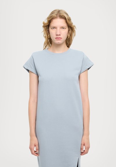 Vestido de algodón de color azul claro con mangas cortas, escote redondo y aberturas laterales. Diseño sencillo, textura suave, largo a la rodilla, ajuste casual.