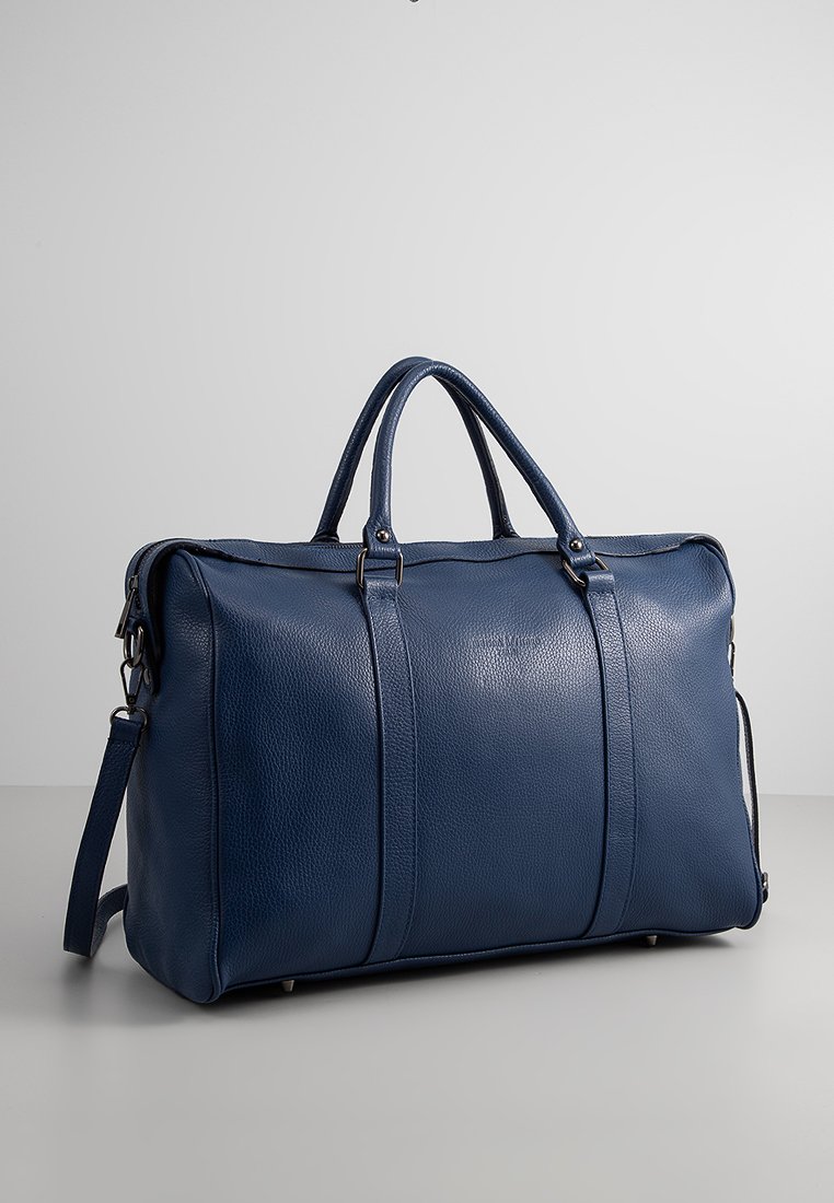 Blaues Leder-Reisetasche mit strukturierter Oberfläche, zwei oberen Griffen und verstellbarem Schultergurt. Merkmale Metallbeschläge und kontrastierende Nähte.