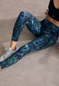 Leggings aderenti con un motivo foglioso multicolore in tonalità di verde e blu. Realizzati in un materiale liscio e elastico.