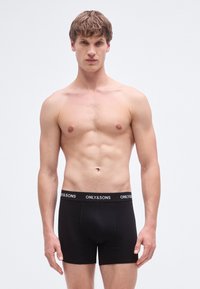 Black cotton boxer briefs with elastic waistband featuring "ONLY&SONS" logo. Smooth texture, fitted design, and mid-thigh length.