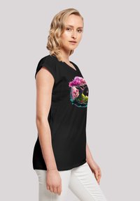 Schwarzes T-Shirt mit kurzen Ärmeln, das ein lebhaftes Bild eines pinken Baums und Laubs zeigt, mit lockerer Passform und weichem Stoff. 