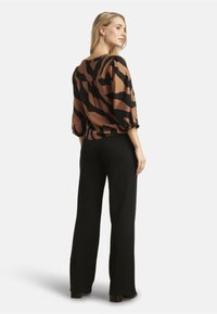 Blusa a strisce marroni e nere con maniche a palloncino, abbinata a pantaloni larghi neri. Tessuto morbido con una vestibilità comoda e scollatura a girocollo.