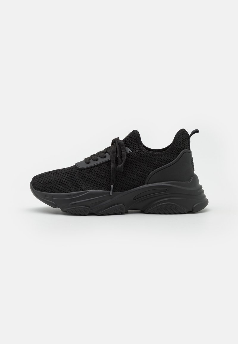 Baskets de sport noires avec une tige en tricot respirante, une semelle texturée et des lacets plats. Elles disposent d'une languette à l'arrière et d'un design sportif.