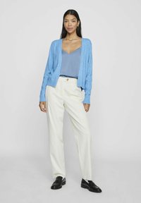 Ljusblå kavaj, V-ringad slate blue topp, off-white vida byxor, svarta loafers. Mjuka texturer, avslappnad passform, minimala accenter.