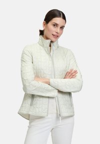 Giacca imbottita verde chiaro con colletto rialzato, zip completa e motivo testurizzato. Presenta tasche laterali e un design dal taglio rilassato.