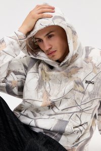 Sweatshirt com capuz com padrão de camuflagem em bege, cinza e branco. Apresenta um bolso canguru e o logótipo "BDG" em preto.