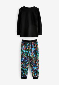 Čierny top s dlhým rukávom skombinovaný s farebnými pyžamovými nohavicami s oslňujúcim motívom multicolor svetiel na čiernom pozadí.