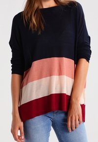 Sweter dziany w paski w kolorach granatowym, różowym, kremowym i bordowym, o luźnym kroju i rękawach 3/4, wykonany z miękkiego materiału i posiadający okrągły dekolt.