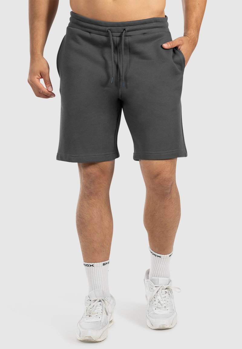 Shorts en coton gris avec taille élastique et cordon de serrage, dotés de poches latérales et d'une coupe décontractée qui s'arrête au-dessus du genou.