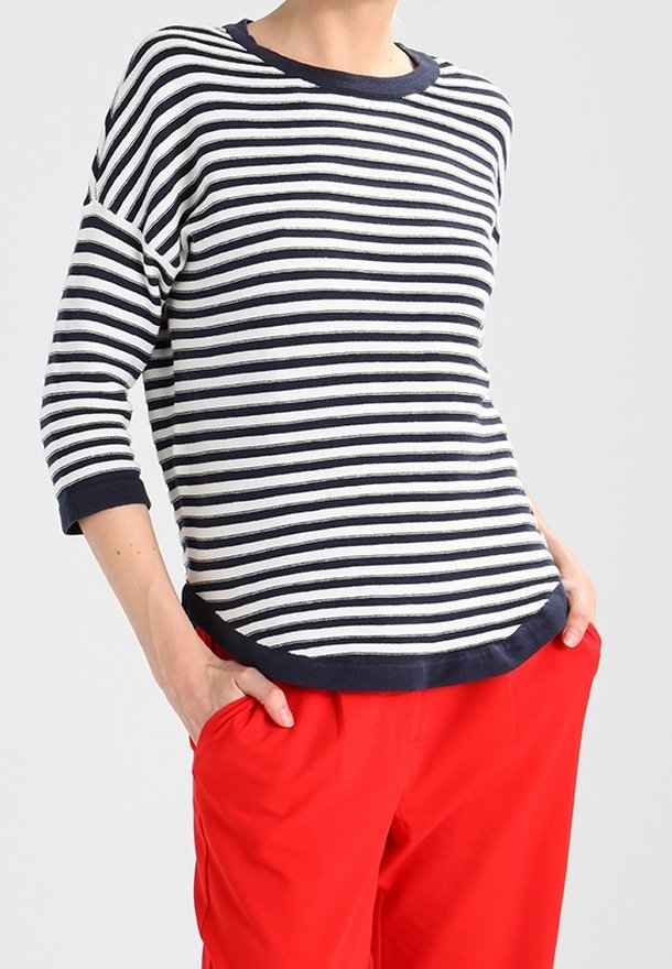 Gestreiftes Langarmshirt in Marineblau und Weiß mit rundem Halsausschnitt und kontrastierendem marineblauen Saum, kombiniert mit roten Hosen.