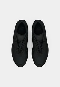 Svarte Nike-sneakers med et strømlinjeformet design, som har en rund tå, teksturert overflate og svarte snøringer. Utsmykket med en subtil logo på tungen.