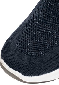 Breathable black knit fabric on a sneaker's toe with subtle blue reflective threads and a white rubber sole edge.