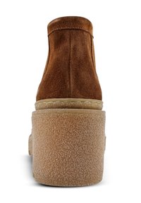 Braune Wildlederstiefelette mit runder Zehenpartie und einer strukturierten, hellen Plattformsohle. Besteht aus glatten Nahtdetails auf der Rückseite.