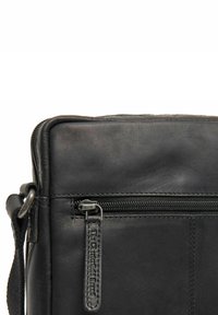 Borsa a tracolla in pelle nera di forma rettangolare, con una tasca frontale con zip e un'etichetta in pelle con il marchio. Texture liscia e cuciture robuste.