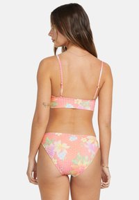 Ružový kvetinový bikini set obsahuje tenké ramienka, priliehavý braletový top a spodný diel s nízkym sedlom s textúrovaným vzorom a farebnými kvetinovými akcentmi.