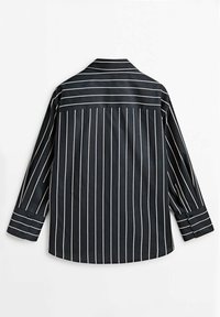Chemise noire à manches longues avec des rayures blanches verticales sur le corps et des rayures horizontales sur le haut du dos et les poignets, vue de dos.